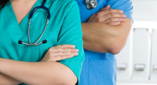 Two doctors are shown in close-up, standing prepared to work with their arms folded across their chests. A concept of Albanian medical document translation.