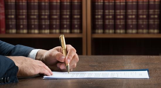 A lawyer signing a legal document with a golden pen. Concept of legal translation services. 
