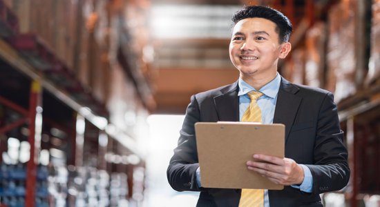 A man in a business suit holding a clipboard and smiling.
