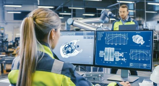 A blonde engineer looking at blue prints and models on two screens.