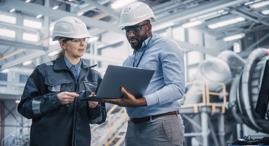 Man and woman in white hard hats looking at a laptop. 