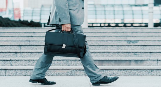 A businessman in a gray suit walking with a black briefcase.