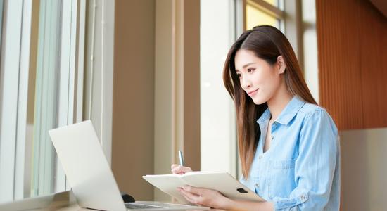 Asian woman working on laptop in an office. 