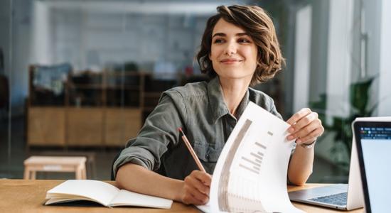 A woman with short hair smiling and working on a clipboard. 