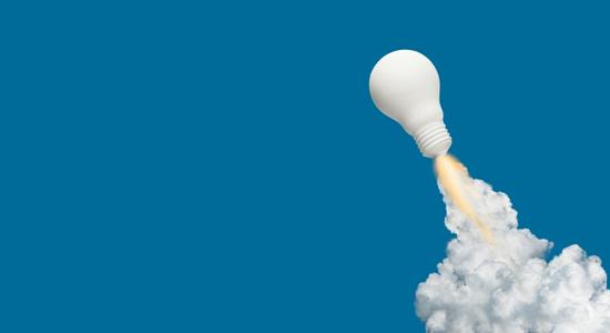 A white light bulb taking off like a rocket against blue background. Concept of multilingual SEO translation services and SEO translated content.