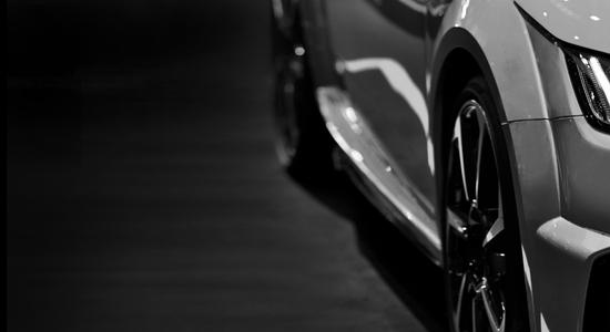 Close-up of left side of a gray car on a gray surface. Concept of automotive translation services.