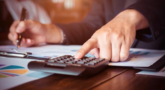 Man working on desk and place finger on calculator. Concept of accounting translation services.