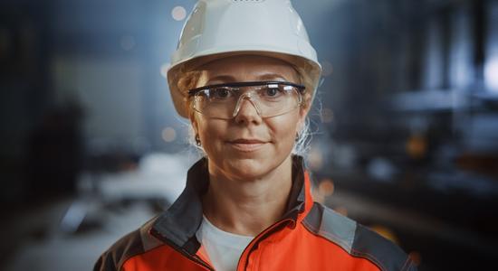 A woman in helmet and safety goggles smiling at camera. 