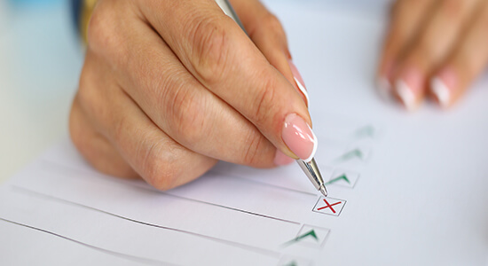 A woman's hand filling in a cross on a piece of paper. Concept of proofreading services and professional proofreaders.