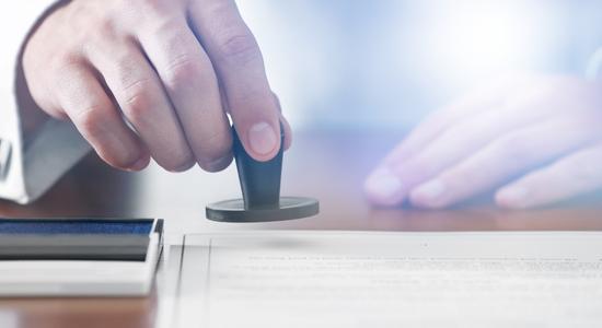 Close-up of a man's hand stamping a legal document. Concept of patent translation services.