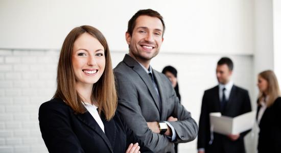 Man and woman in business clothes smiling at the camera.