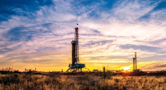 A large oil rig structure at sunset, clouds overhead. Concept of oil and gas translation services.
