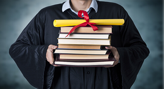 A graduate with black rope holding books and diploma.