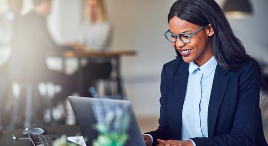 Dark-skinned female employee working on laptop.