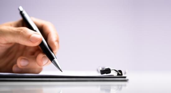 A pen above a clipboard against a lilac background. Concept of compliance translation services.