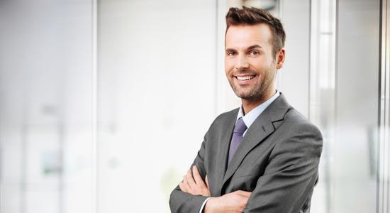 A businessman with crossed arms smiling at the camera.