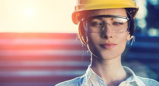A female engineer in hard hat and safety goggles looking at camera.