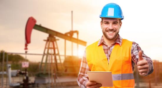 Oil and gas worker in safety gear smiling and giving a thumbs up. 