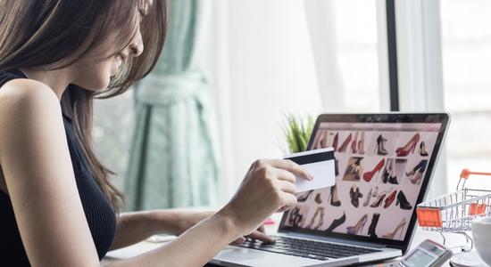 A woman's arm and profile as she looks at shoes on a laptop screen. Concept of eCommerce translation and ecommerce localisation.