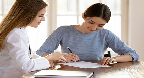 A young woman signing medical agreement in a meeting with a female doctor. Concept of medical translator.