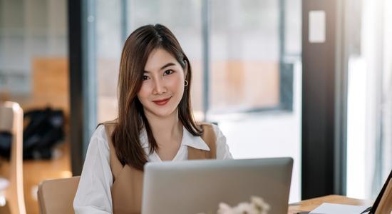 A woman in business clothes with a laptop smiling at camera. Concept of contract translators.