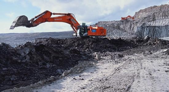 Two orange Hitachi excavators at a digging site. Concept of renewable energy translation and mining translation.