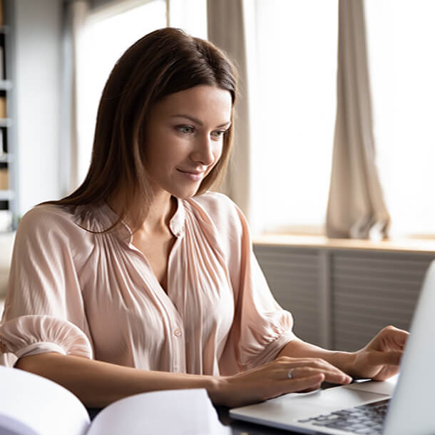 A professional smiling businesswoman standing in office with folded hands.
