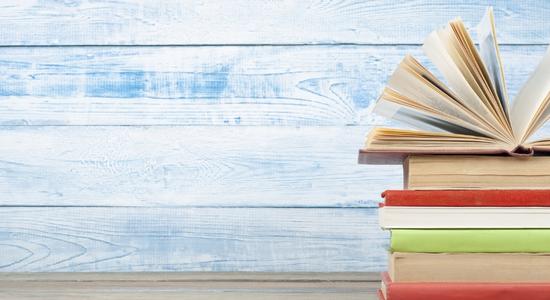 A stack of books in front of a blue wood background. Concept of publishing translation services.
