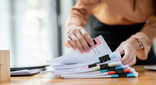 Man working with stack of files on desk. 