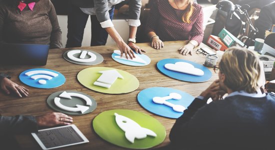People discussing marketing at a conference table with colourful marketing/digital symbols. Concept of marketing translation services.